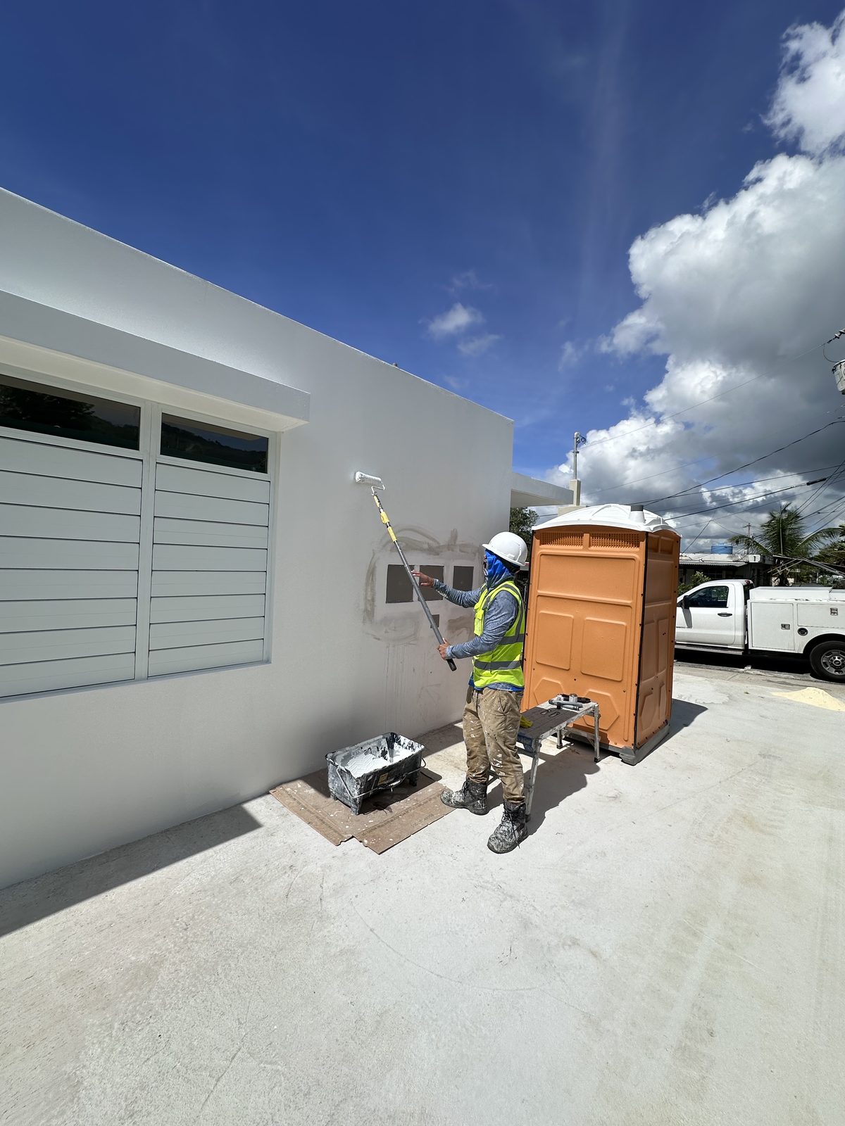 KLJ painter rolling paint on a building's exterior wall